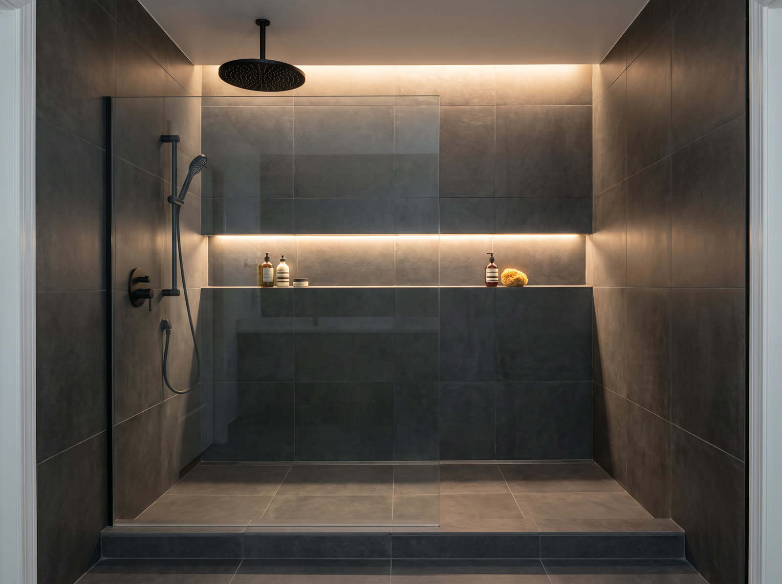 Modern walk-in shower remodel with dark tile and matte black rainfall shower head